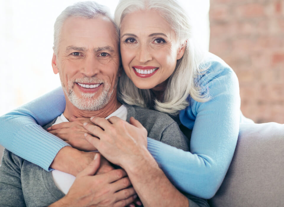 Image of smiling elder woman holding an elder smiling man from back