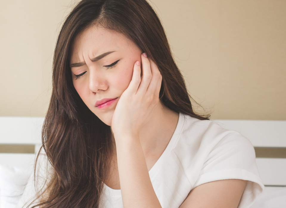 Image of a model girl feeling pain of her teeth by holding her left side of the face