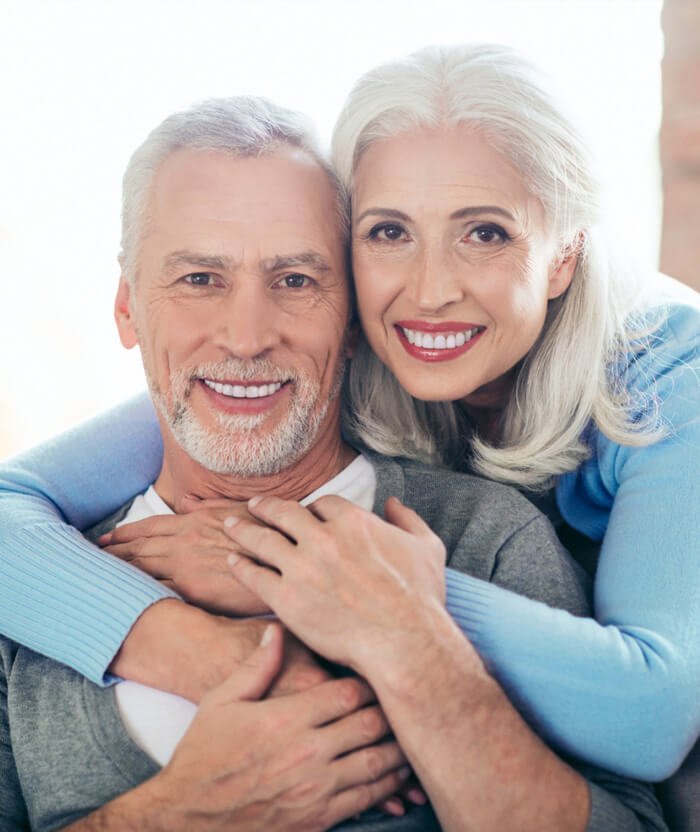 Image of smiling elder woman holding an elder smiling man from back