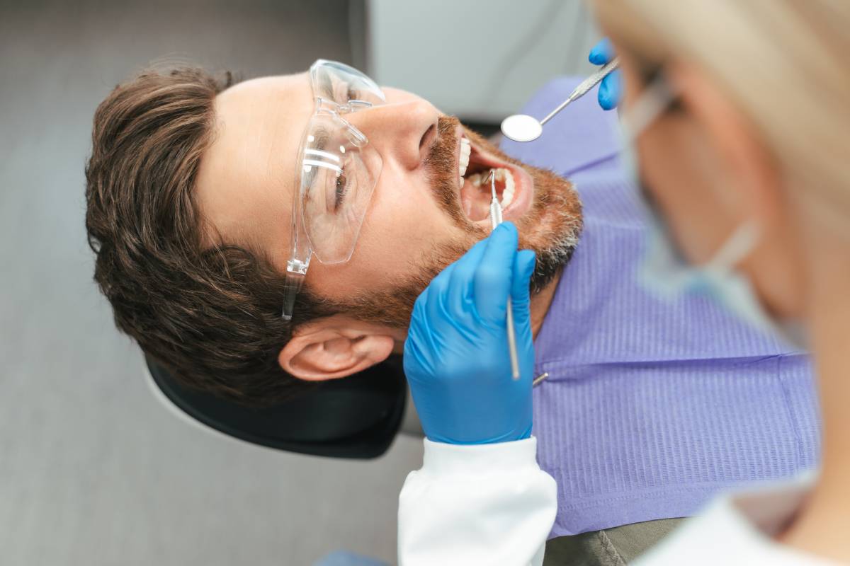 Dentist examining patient’s teeth with dental tools, checking for cavities in support teeth for dental bridges